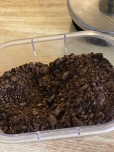 coarse ground coffee grounds in clear container on wooden counter 
