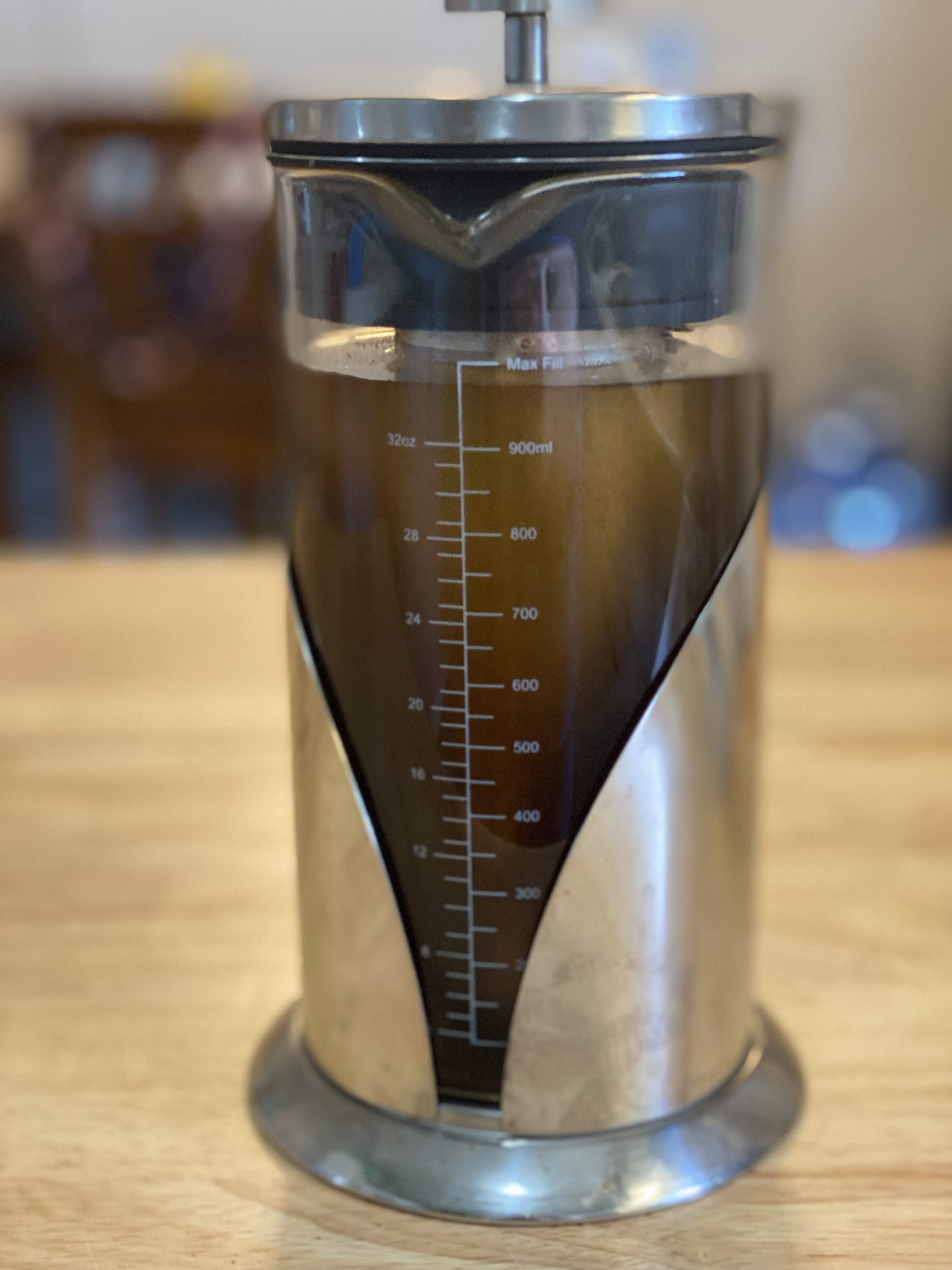 metal and glass pitcher with brown water on wooden counter
